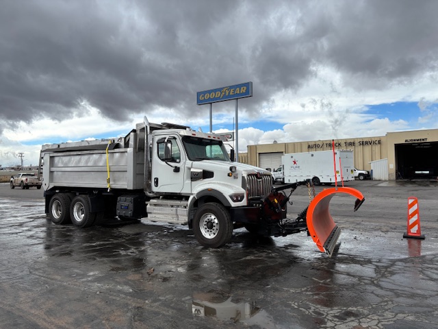 Front view of Jensen snow plow mounted on Warren stainless dump truck for municipal snow operations.